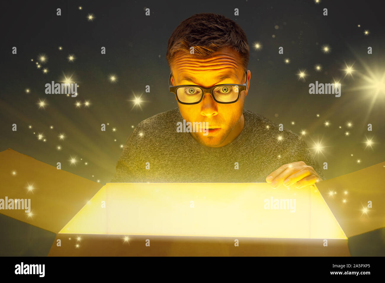 Amazed man next to a magically glowing parcel Stock Photo