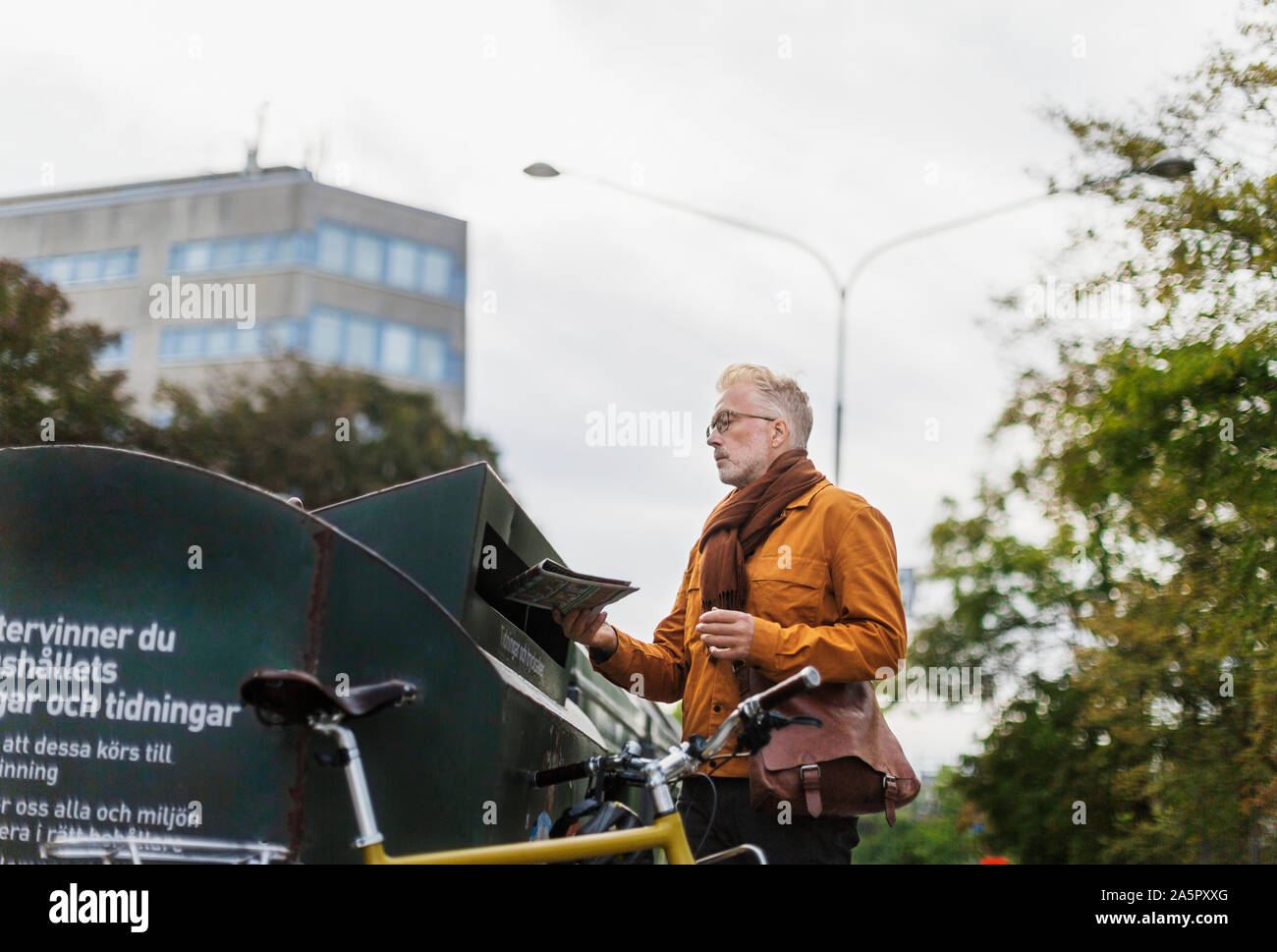 Man putting newspaper into recycling bin Stock Photo
