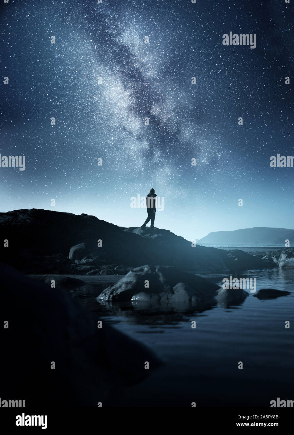 Calm Midnight adventures. A long exposure shot of a man staring up into the night sky, silhouetted against the milky way galaxy. Photo compsoite. Stock Photo