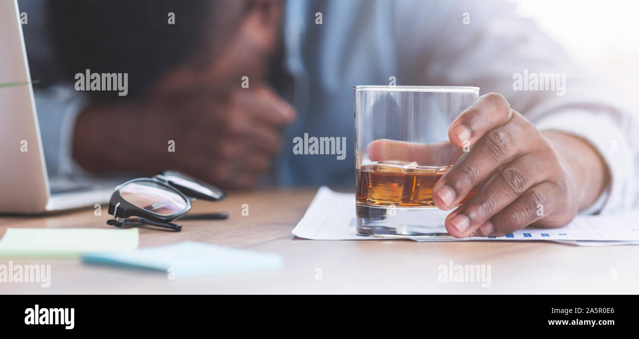 Drunk businessman sleeping at workplace with whiskey glass in hand Stock Photo