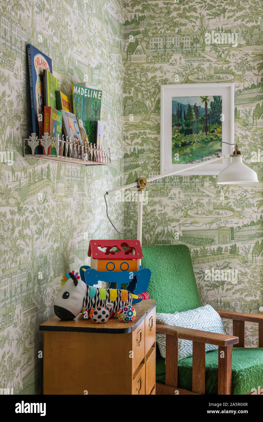 Wall mounted shelf above toybox with armchair in child's nursery Stock Photo