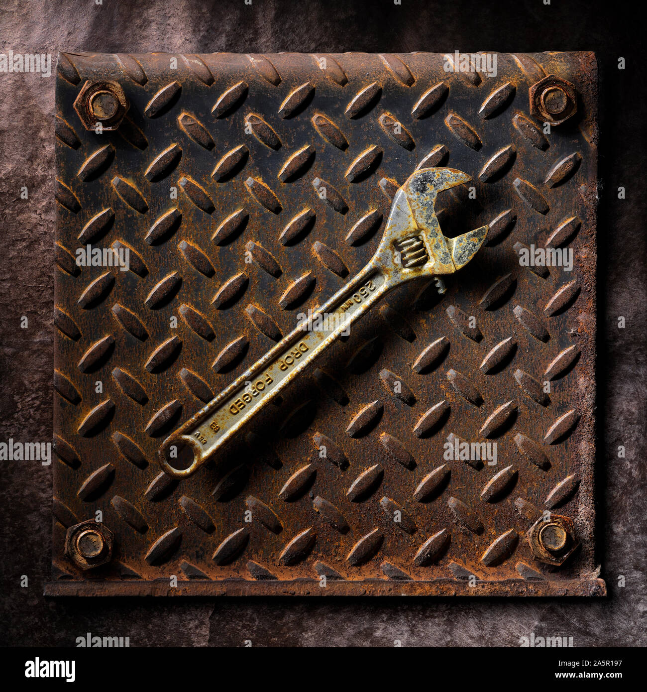 Old rusty wrench on rusting diamond plate steel artistic fine art Stock Photo