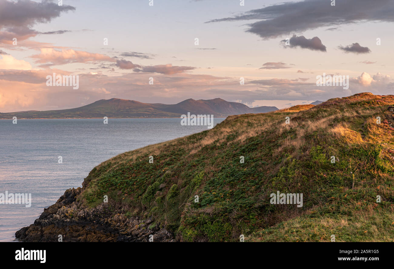 View of the llyn peninsula from Ynys Llanddwyn on Anglesey, North Wales at sunset. Stock Photo