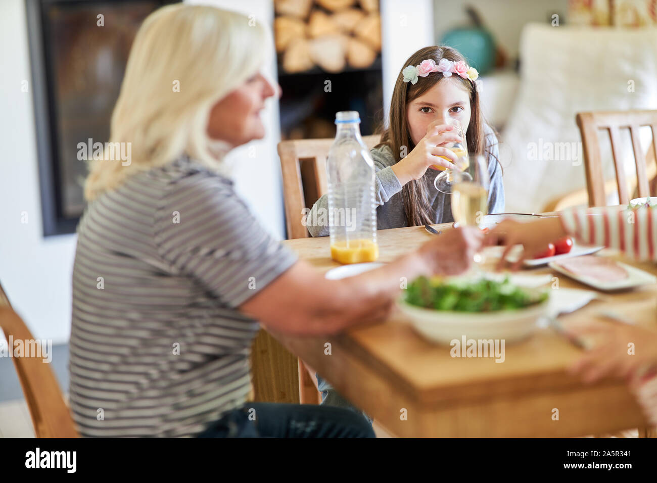Girl is drinking a juice while having lunch with grandmother in the foreground Stock Photo