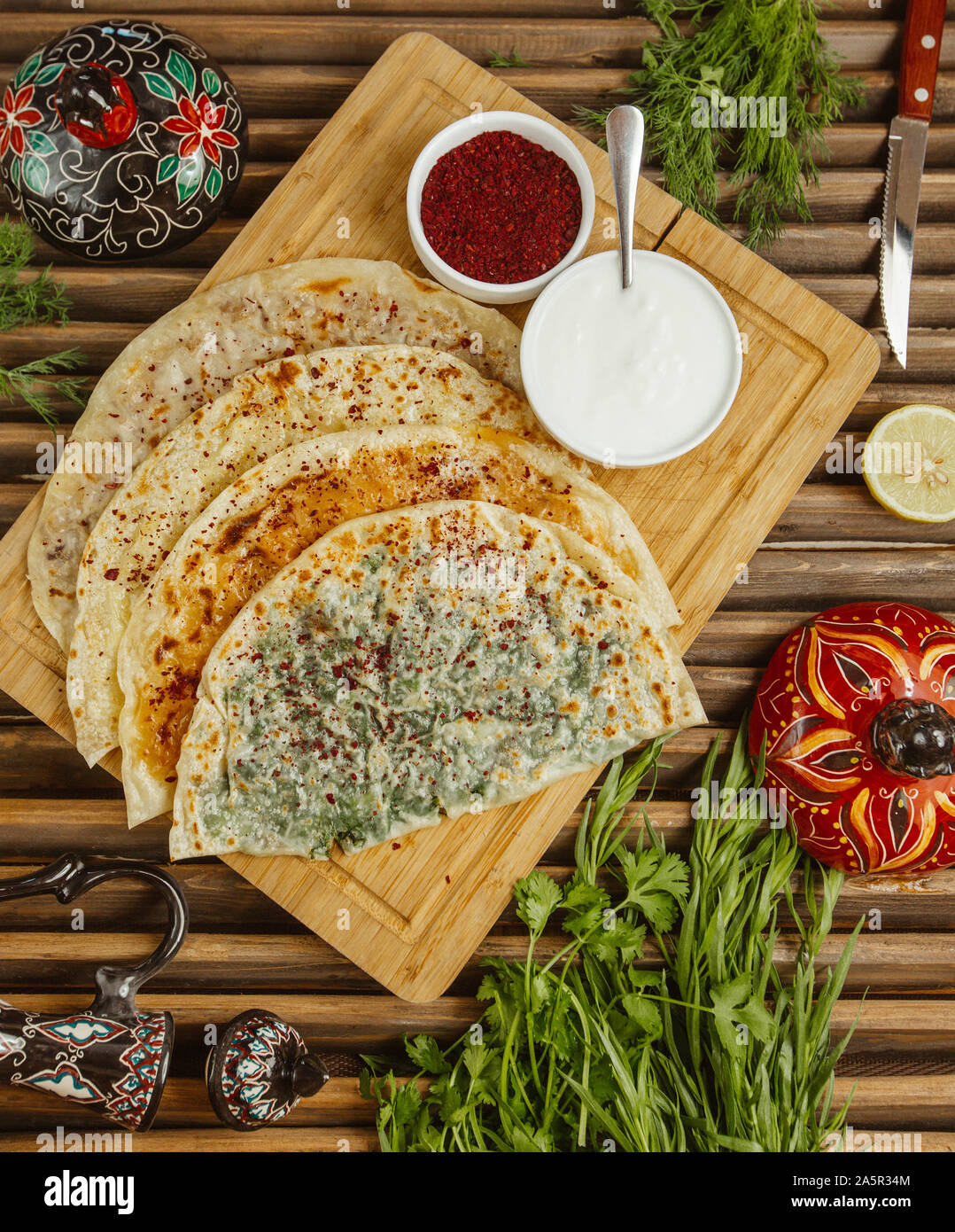 gutab stuffed flatbreads served with sumac and yoghurt on wood board