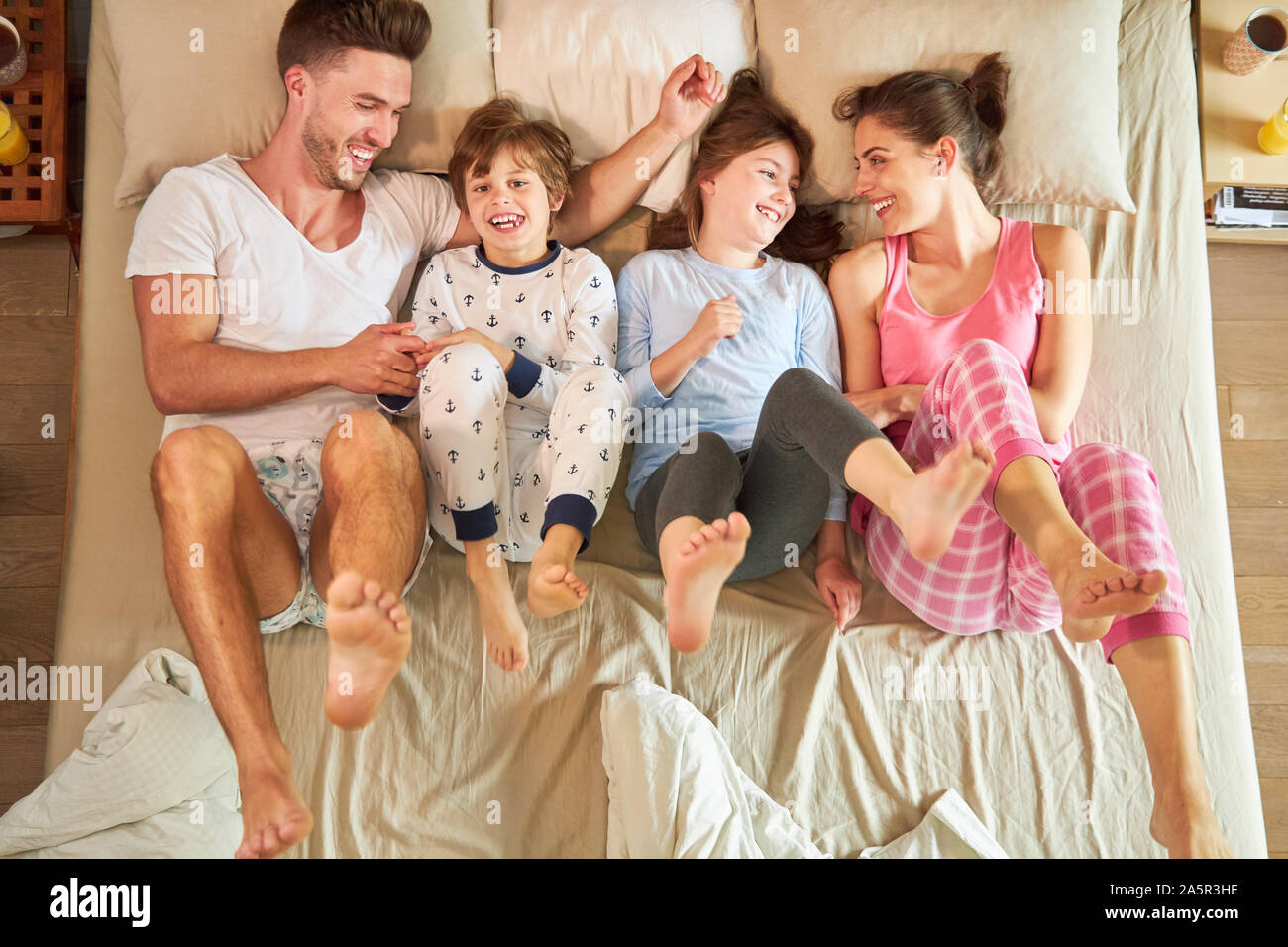 Parents play with their children in bed and kick their feet Stock Photo