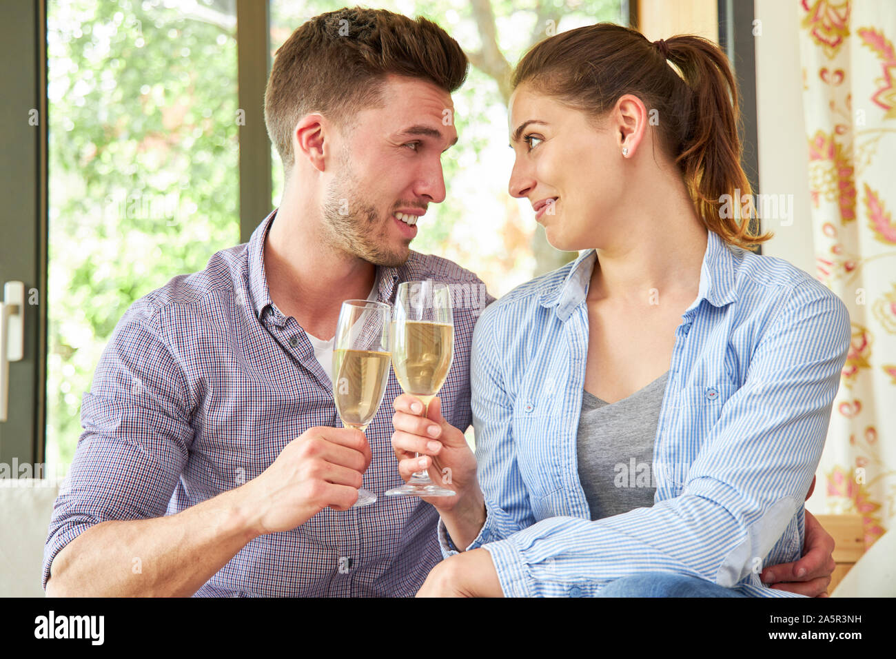 Young couple in love celebrates engagement or reconciliation with a glass of sparkling wine Stock Photo