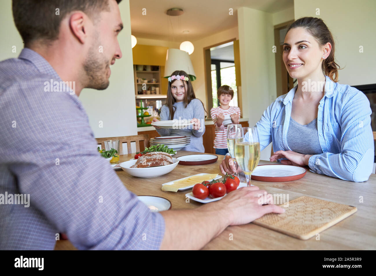 Children help parents in the household and bring plates of food to the table Stock Photo