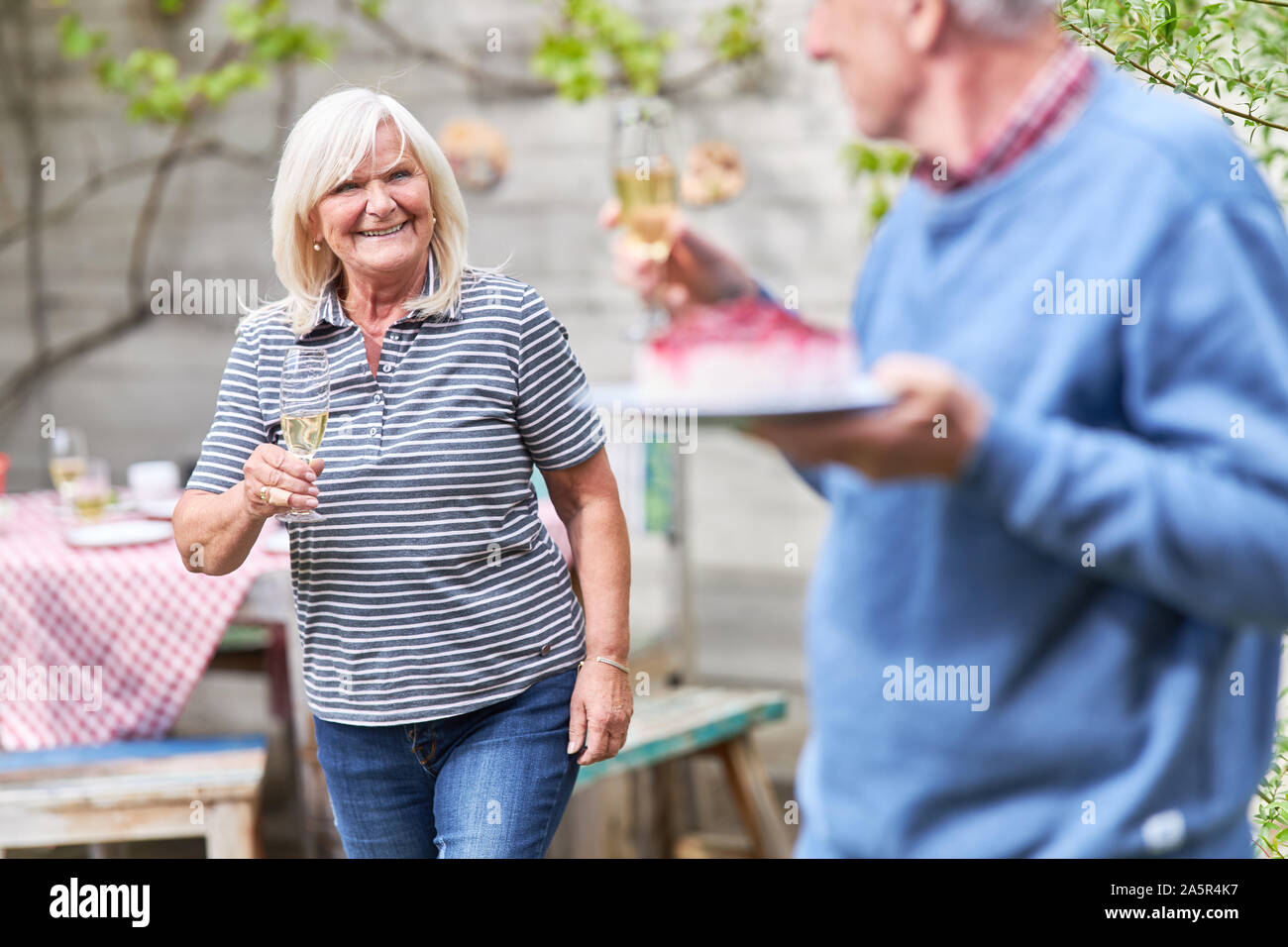 Senior couple on a summer party celebrating with champagne and cake in the garden Stock Photo