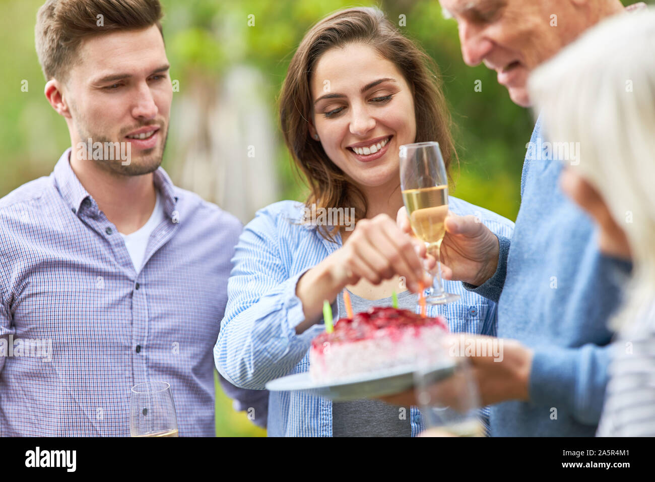Woman decorates birthday cake with candles on a family celebration in the garden Stock Photo