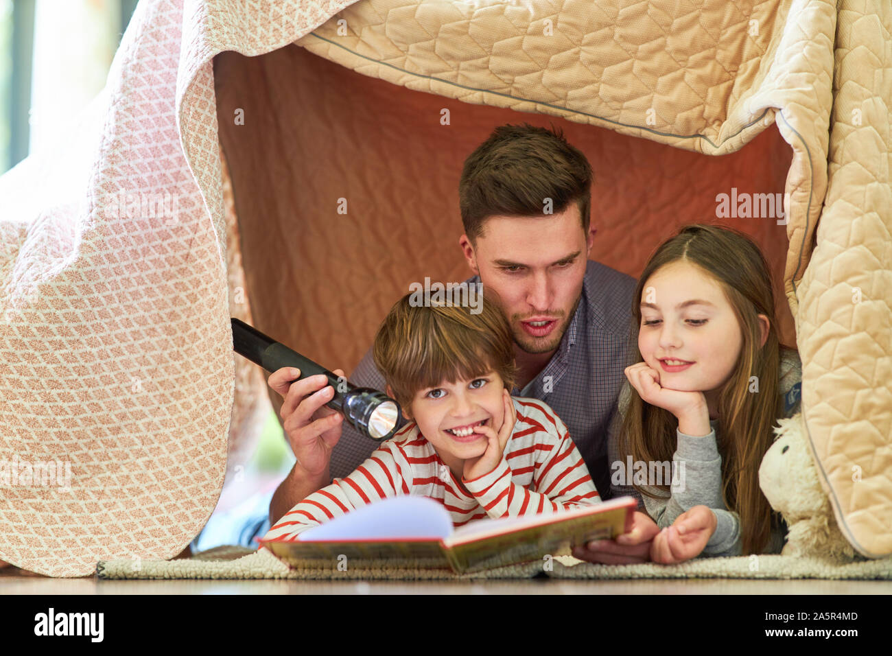 Father is reading an exciting story from a book to his children Stock Photo