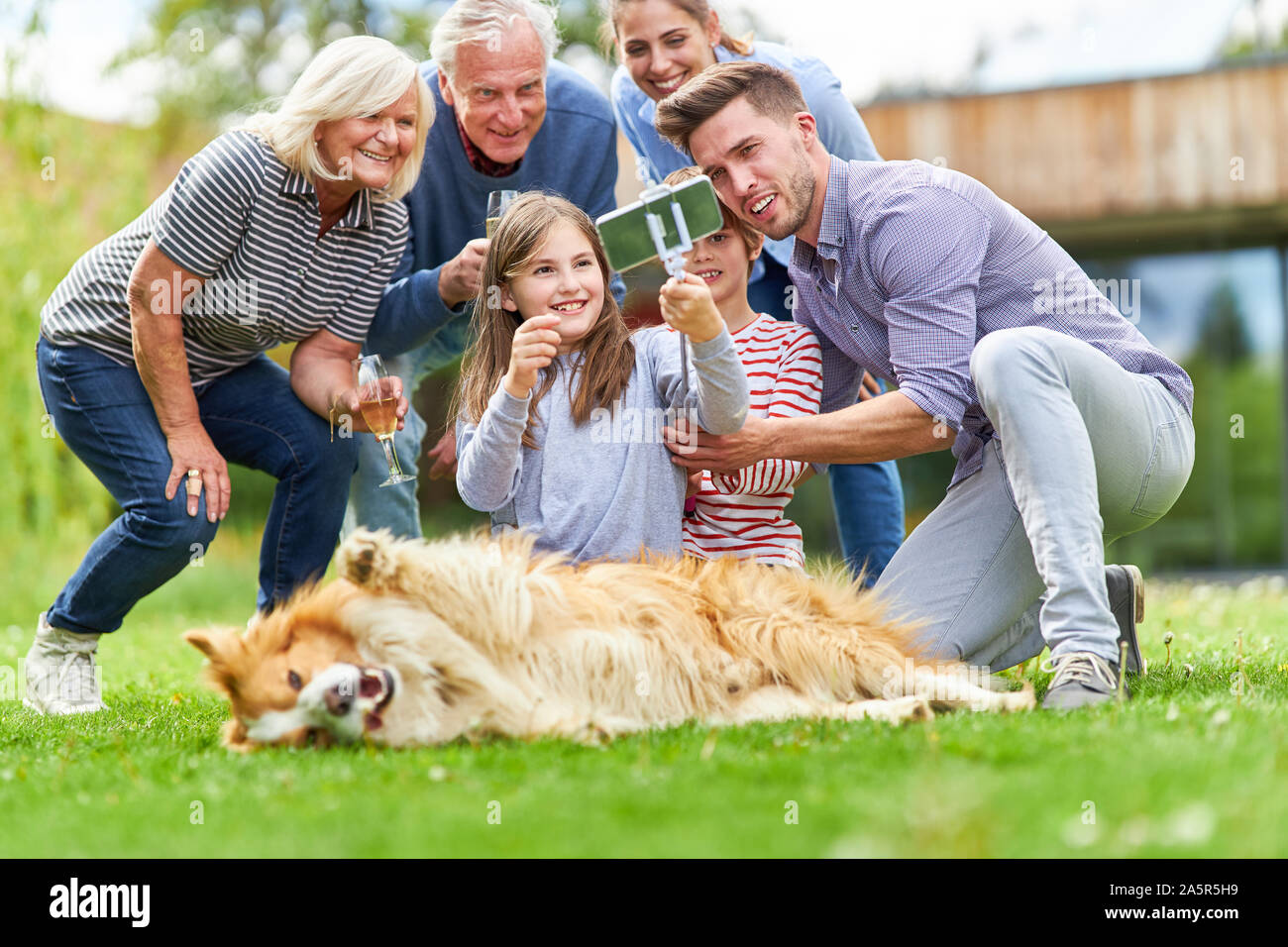 Happy family with grandparents and children makes a selfie in the garden with dog Stock Photo