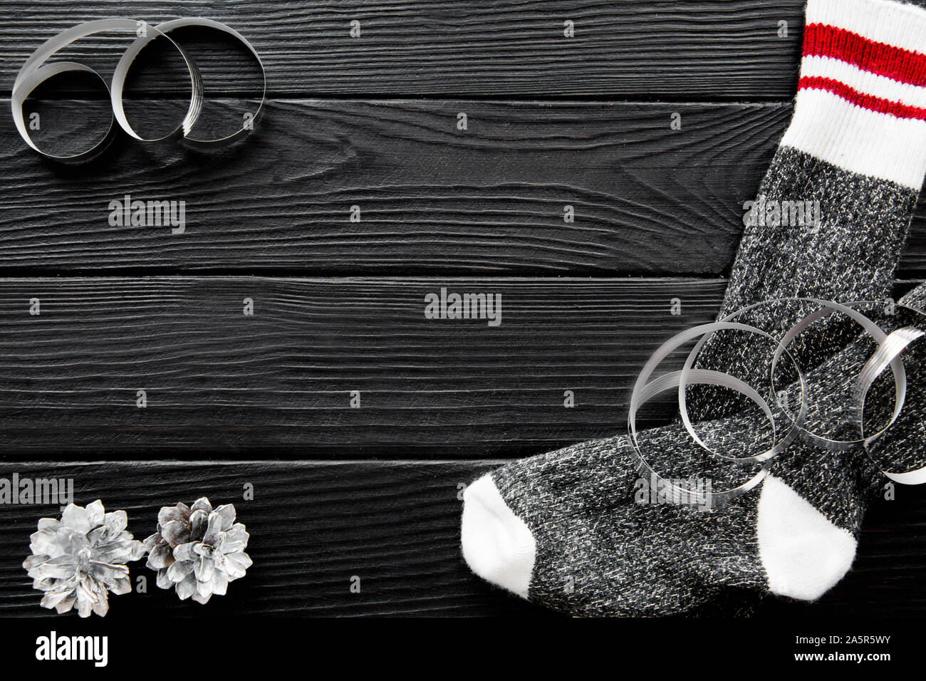 Christmas socks on black wooden table. Silver cones, ribbons and serpentines. Space for text, free space for text, copy space, top view. Stock Photo