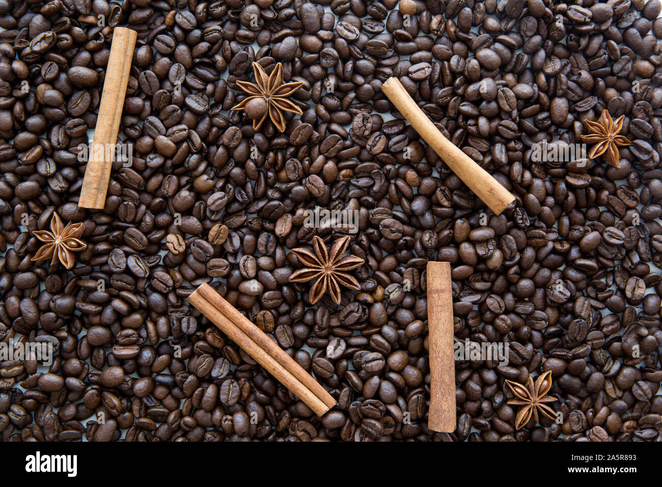 Cinnamon sticks and anise stars spices on roasted coffee beans background. Stock Photo