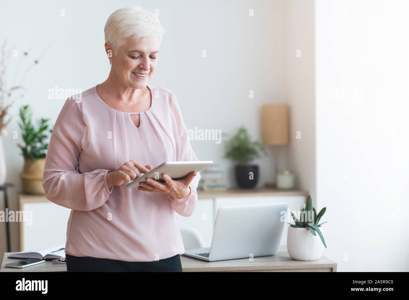 Smiling beautiful senior woman using digital tablet Stock Photo