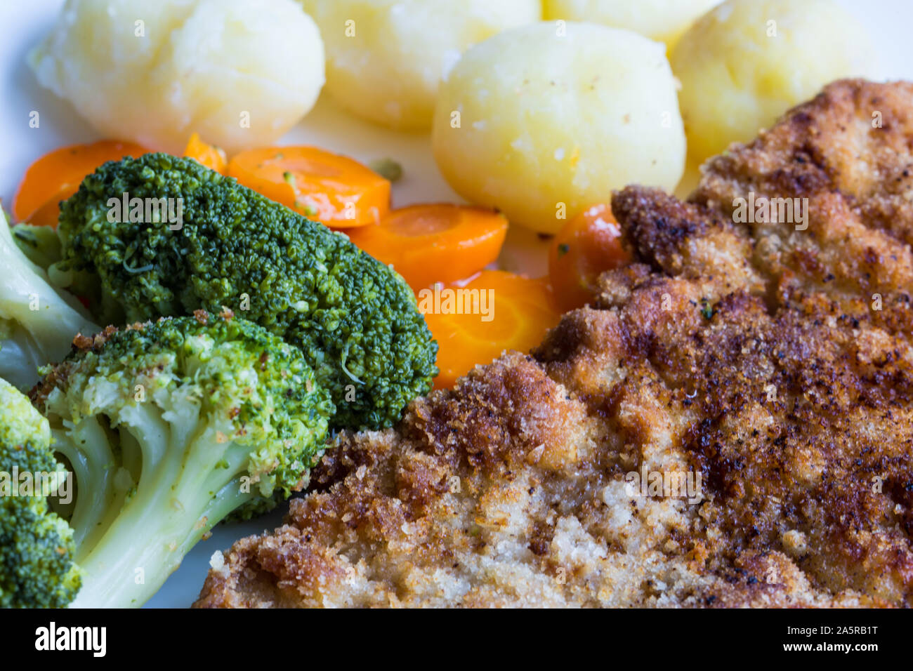 Pork cutlet with boiled vegetables, potatoes and onions. Austrian schnitzel with garnish. Top