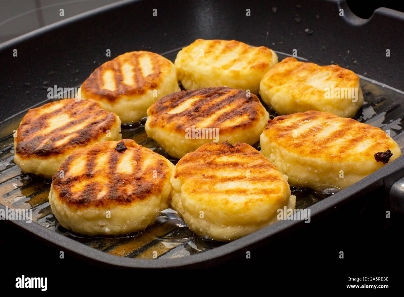 Traditional Russian sweet syrniki cottage cheese pancakes cooking process in the frying pan Stock Photo