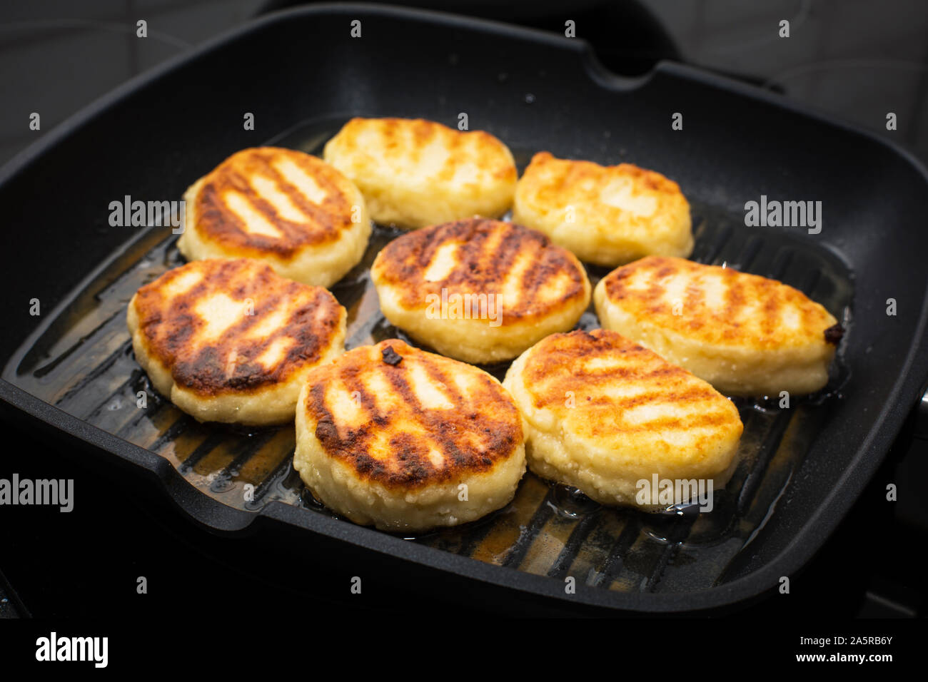Traditional Russian sweet syrniki cottage cheese pancakes cooking process in the frying pan Stock Photo