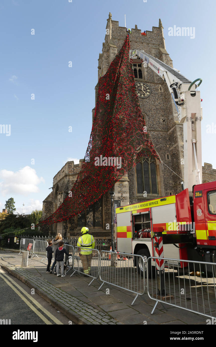 Suffolk firefighters cover St. Peters Church, Sudbury in a net of knitted poppies to commemorate Armistice Sunday. Stock Photo