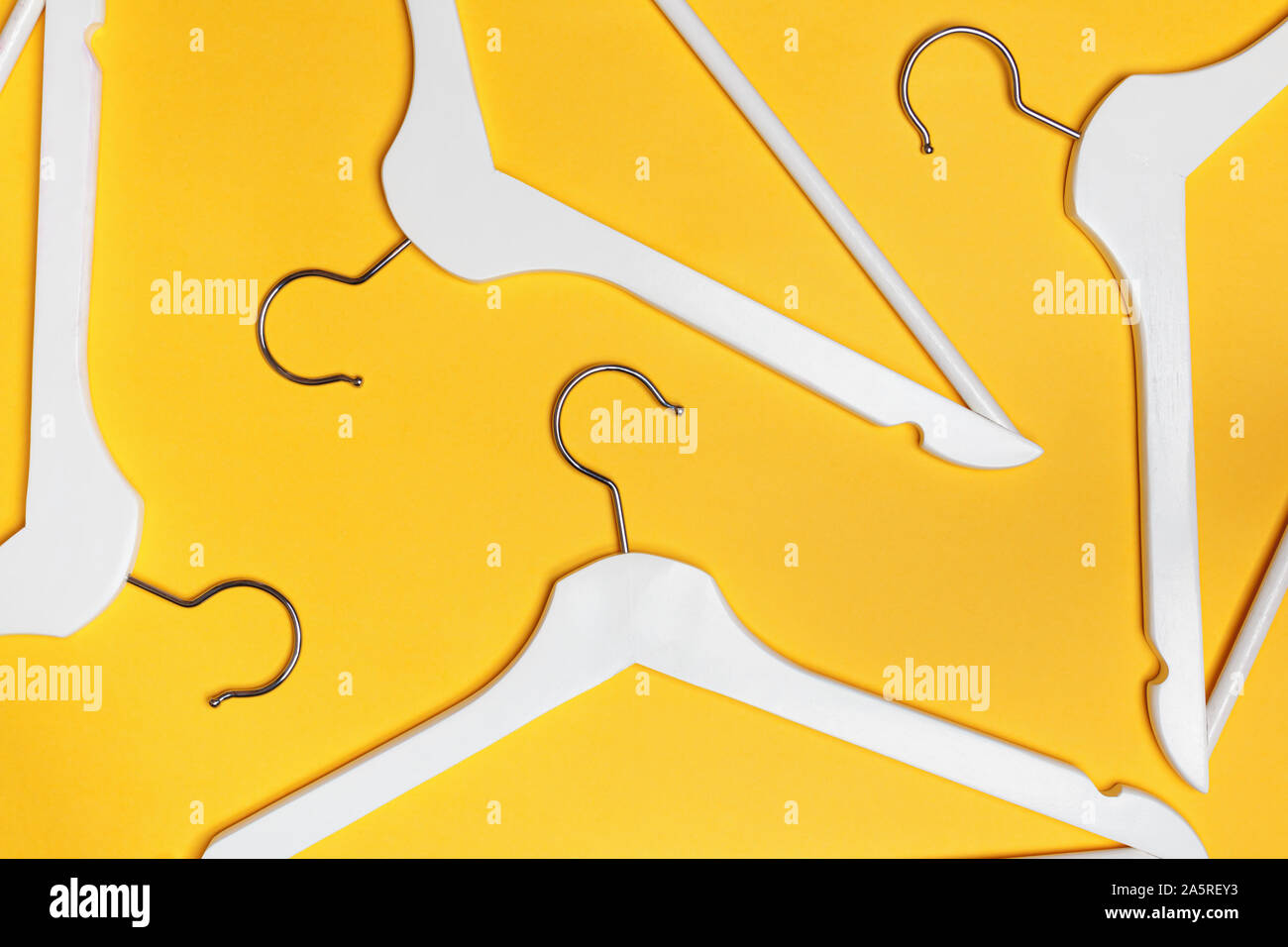 White hangers on a yellow background. Flat lay. Top view. The concept of shopping, sales, storage. Stock Photo