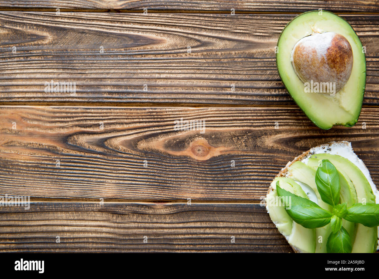 Avocado sandwich with cream goat cheese on brown wooden table. Top view. Free space for text, copy space. Stock Photo