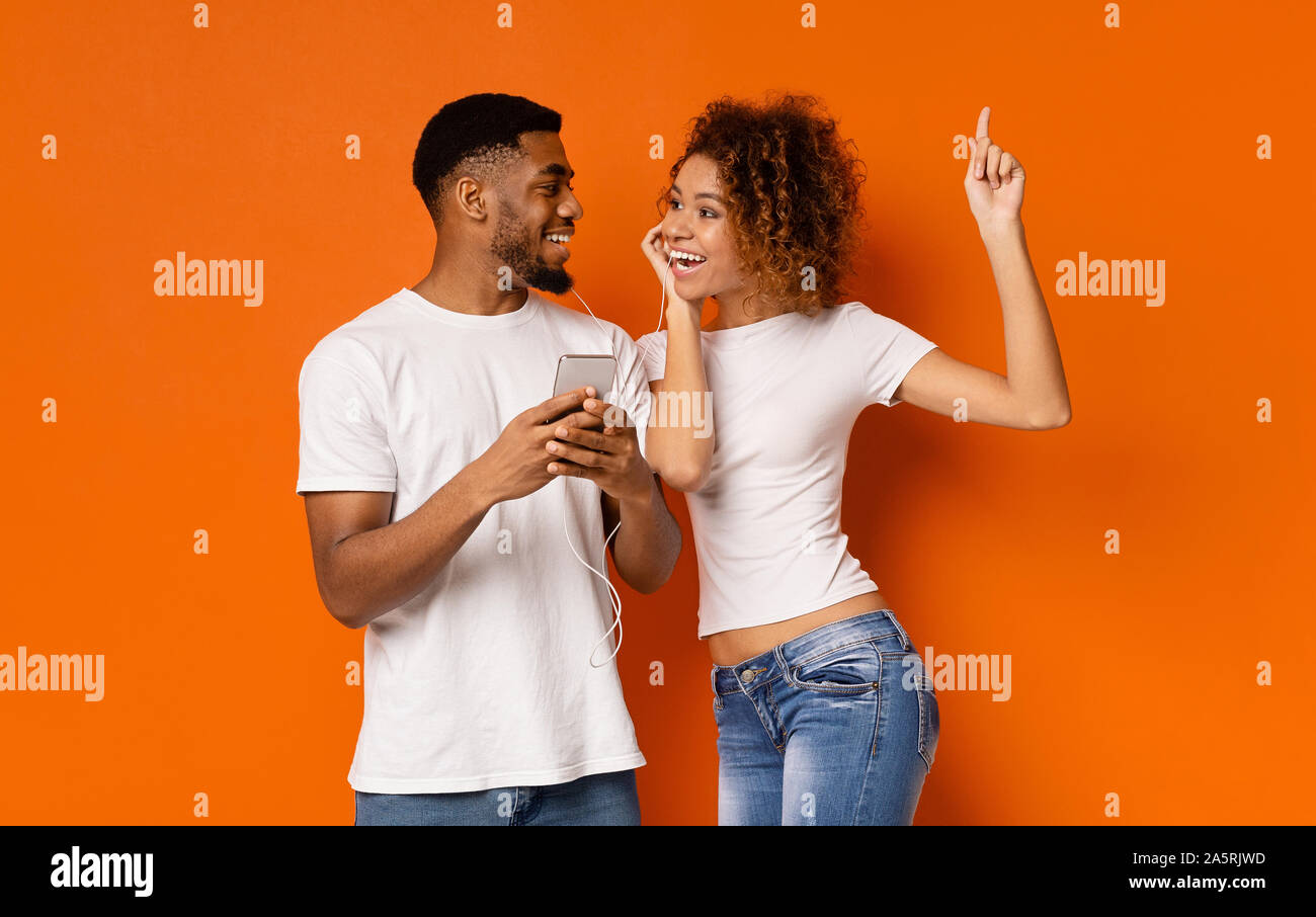 Young black couple enjoying favorite music on cellphone Stock Photo