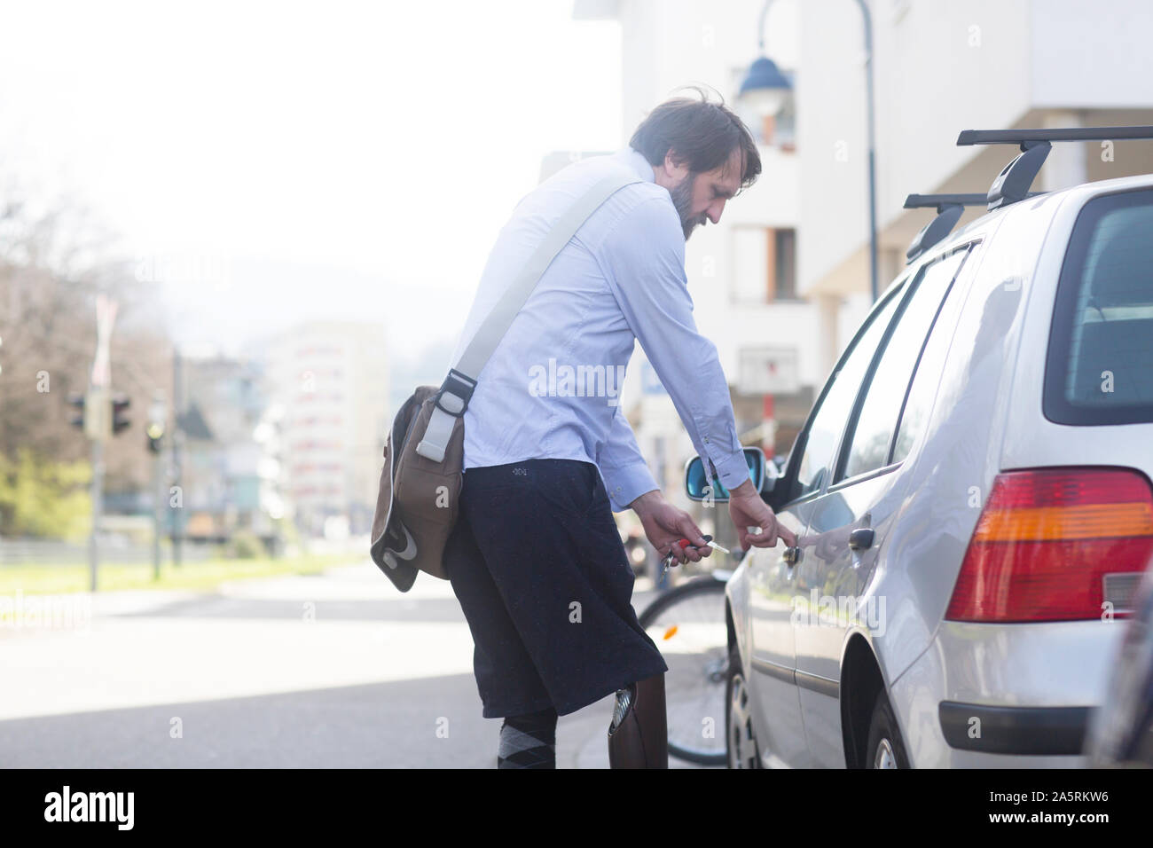 older man with prosthetic leg opening car Stock Photo