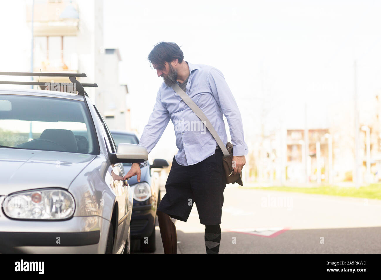 older man with prosthetic leg opening car Stock Photo