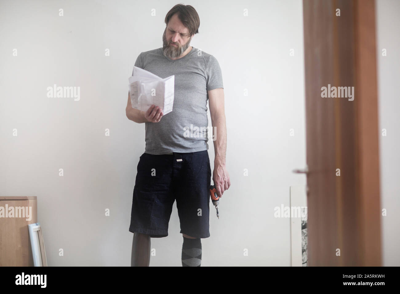 older man with prosthetic leg  working at home Stock Photo