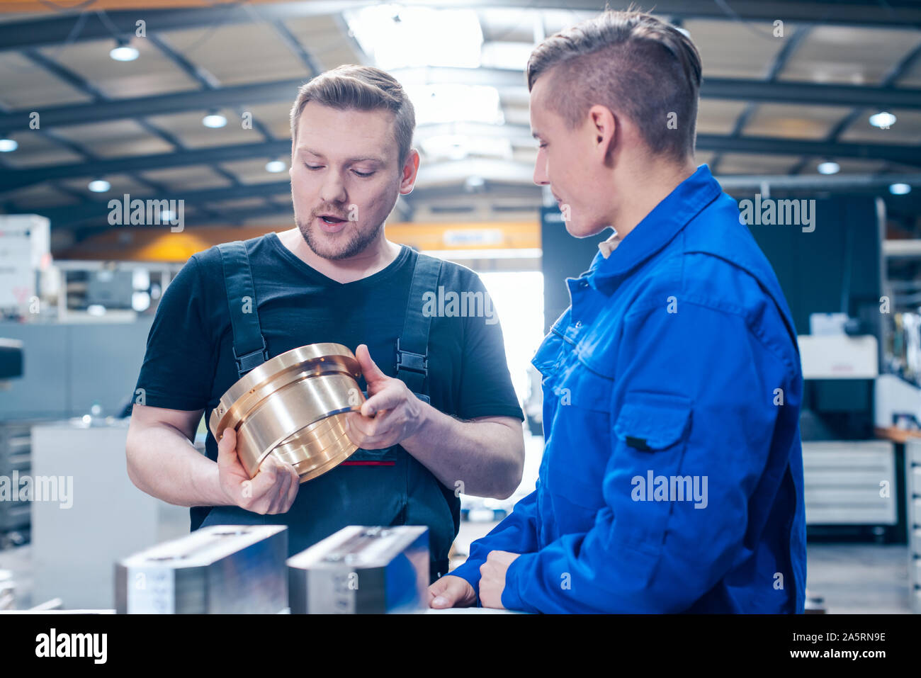 Master discussing a workpiece with his apprentice or trainee Stock Photo