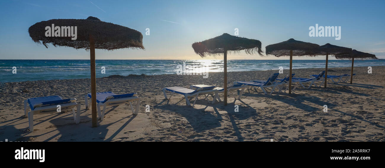 Wicker parasols and sun beds on Son Bou Beach Menorca Stock Photo - Alamy
