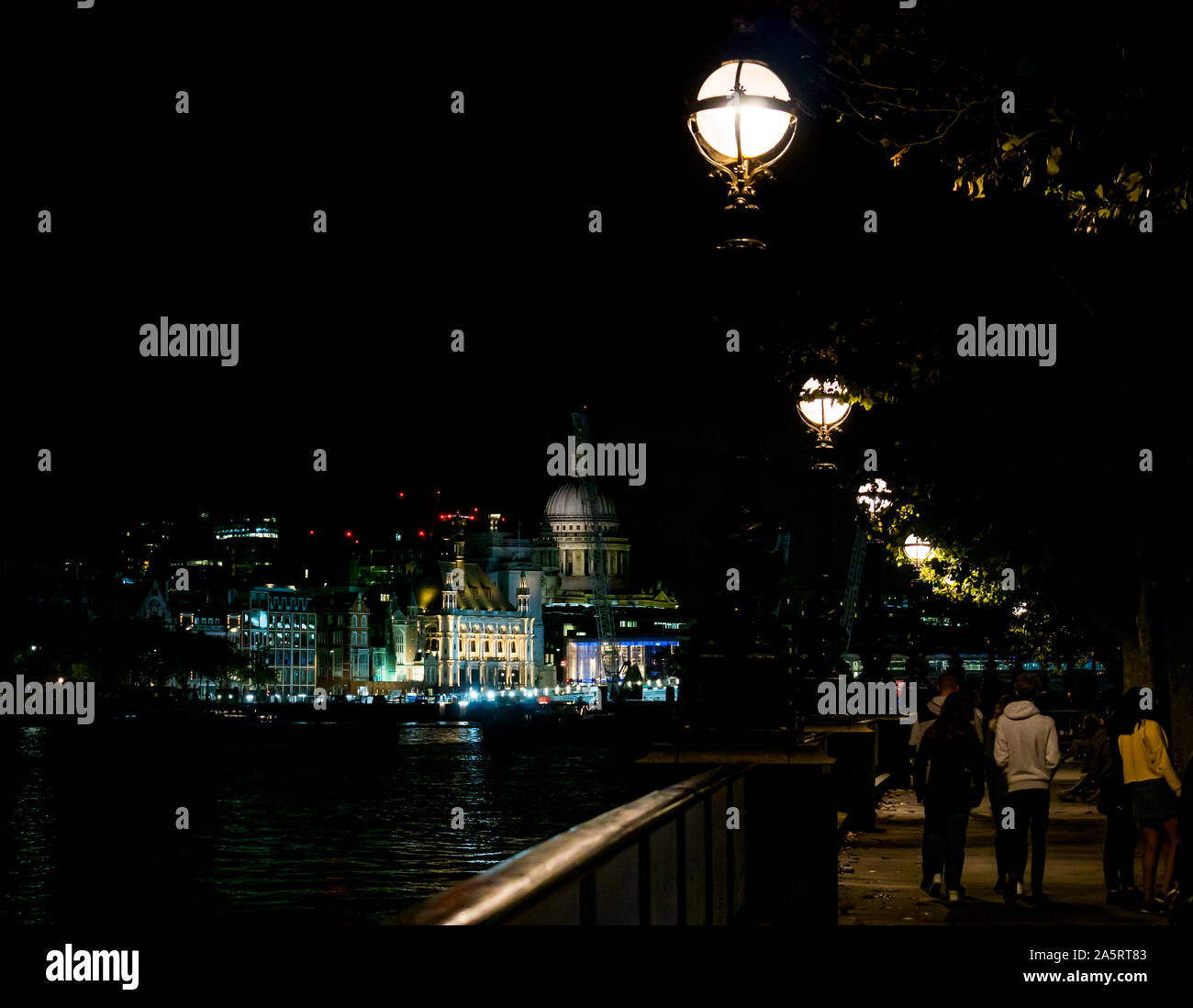 Ornate streetlights along Thames River at night with view of St Paul's Cathedral, London, England, UK Stock Photo