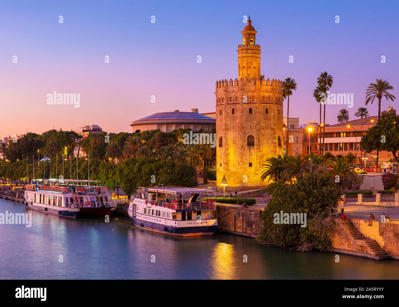 Tour boats at night moored on the Guadalquivir river bank near the Torre del Oro Seville Spain Paseo de Cristóbal Colón seville Andalusia EU Europe Stock Photo