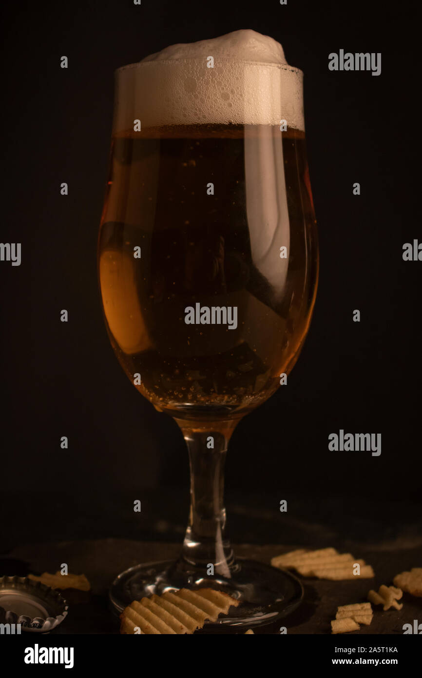Full glass of beer in a dark setting. Stock Photo