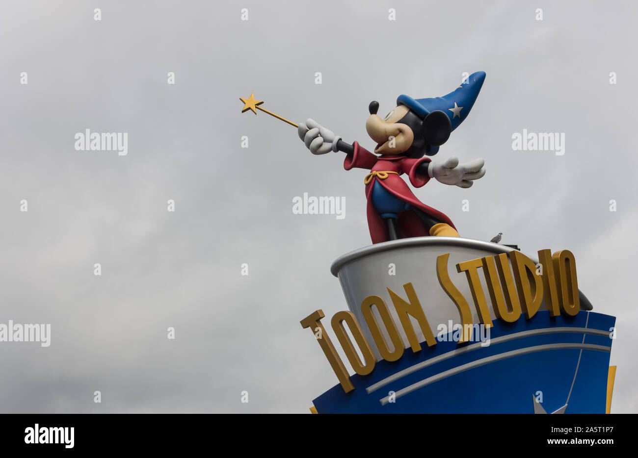 A picture of a statue of Mickey Mouse, as a Sorcerer, at the top of a Toon Studio sign, in Disneyland Paris. Stock Photo