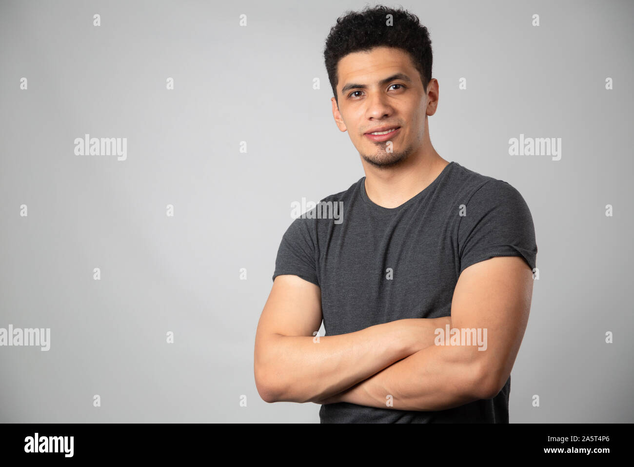 Hispanic man smiling in studio with gray background Stock Photo