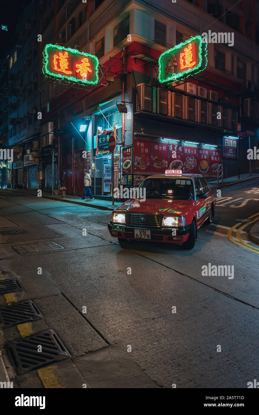Red Taxi in Hong Kong below colored neon signs advertising businesses