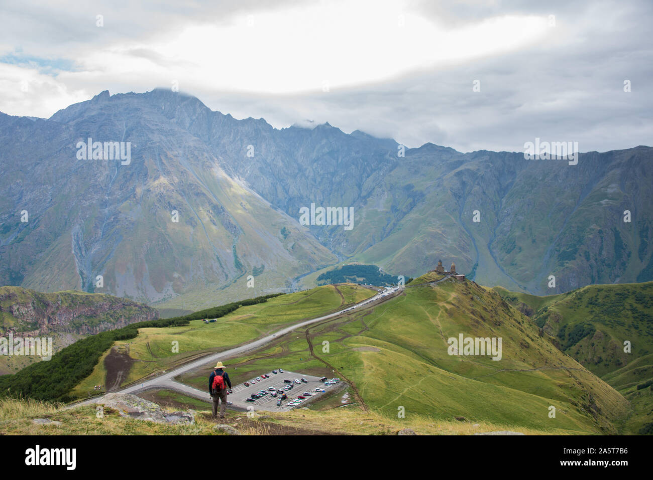 View from top hill on parking place and tourist. Gergeti Holy Trinity Church in Kazbegi, Georgia Stock Photo