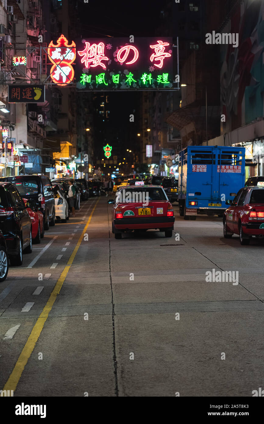 Red Taxi in Hong Kong below colored neon signs advertising businesses