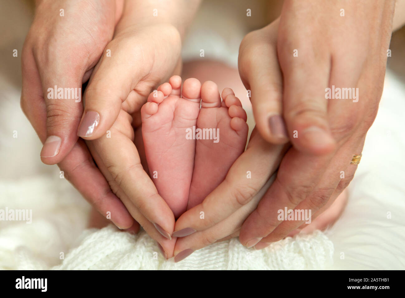 Parenting hands hold the newborn baby's soles. Macro shoot. Conceptual picture for family love, newborn, adoption, baby. Stock Photo