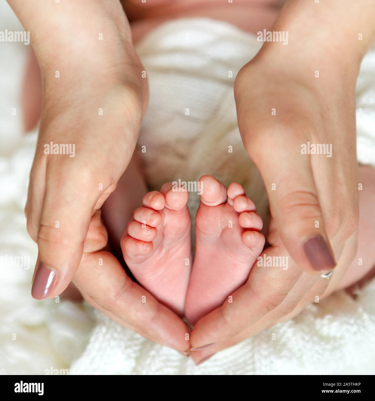 Mom's hand holds baby's foot macro shoot. Conceptual picture for family love, newborn, adoption. Stock Photo