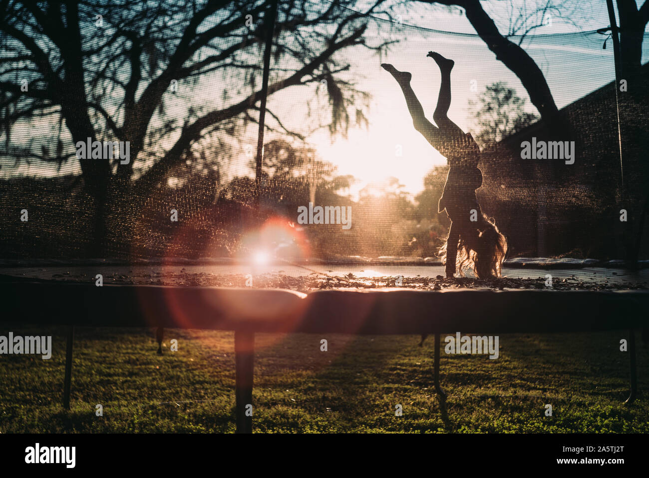 young girl on trampoline at sunset Stock Photo