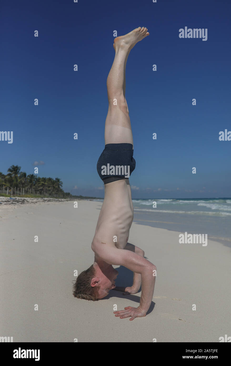 Man doing headstand on beach Stock Photo
