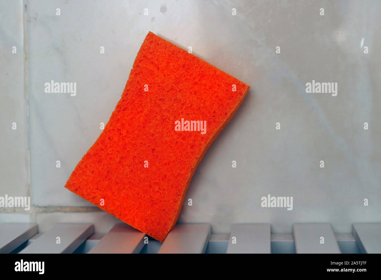 Orange sponge on a table in the sink. Stock Photo