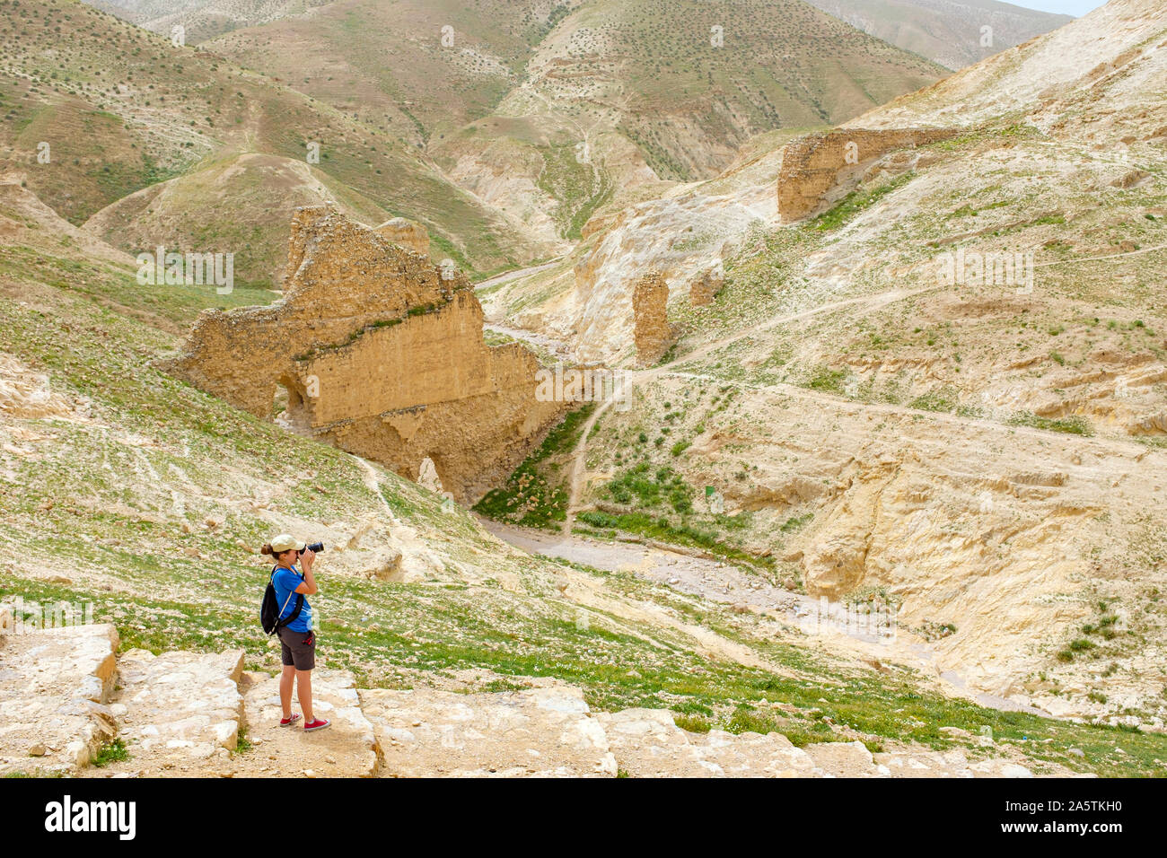 Hikers pass in front of Ruins of ancient aqueduct in Wadi Quelt, Prat River Gorge, Jericho Governorate, West Bank, Palestine. Stock Photo