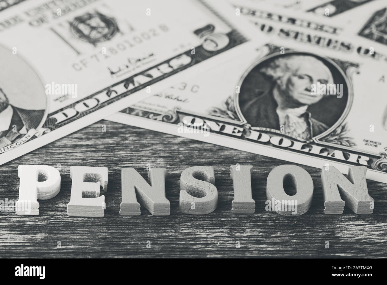 black and white macro photo with the English word -pension- in front of dollar banknotes in matt look Stock Photo
