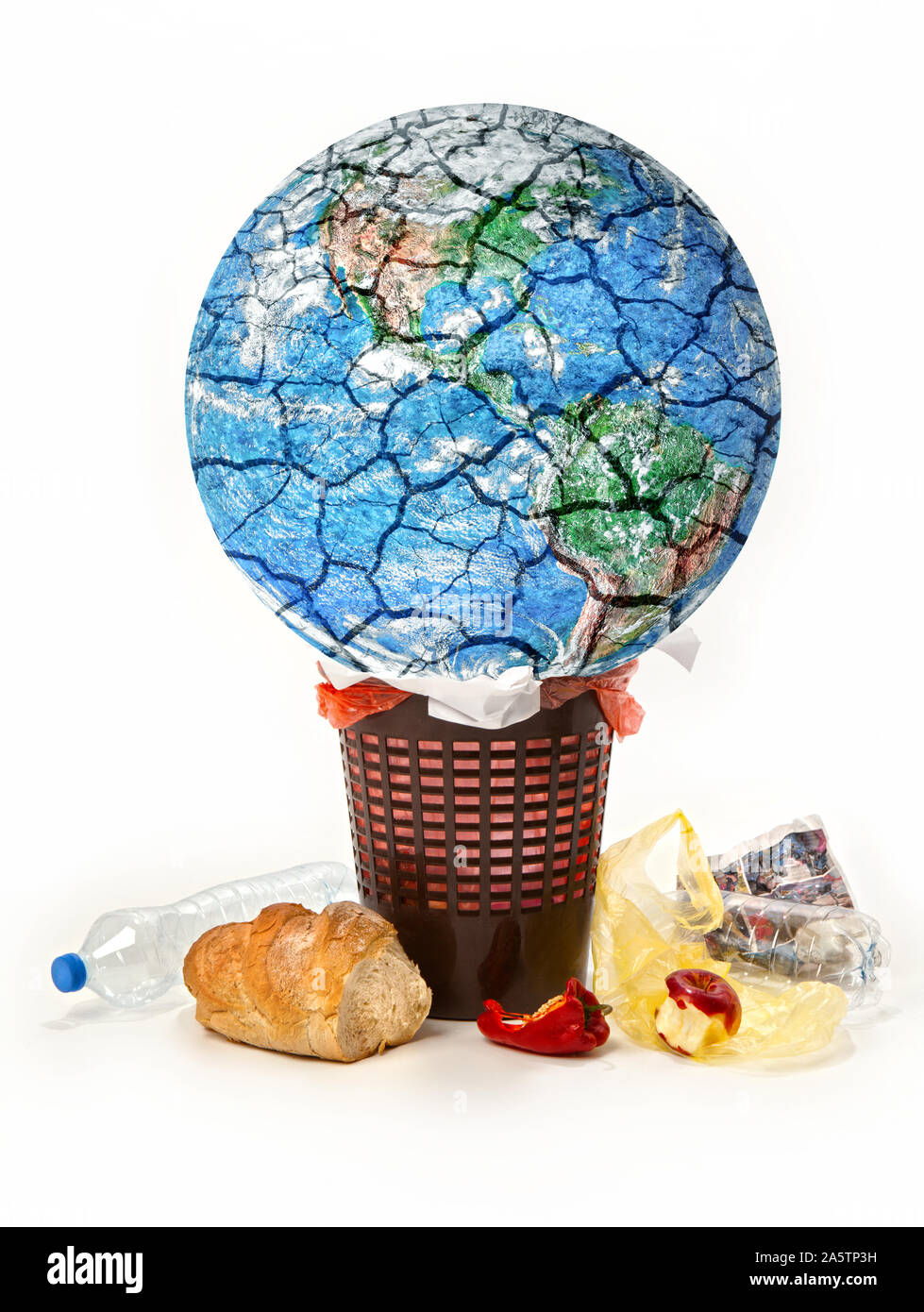 Conceptual image of planet destroying. Planet Earth is thrown into garbage, discarded food, waste,trash,  isolated on a white background. Stock Photo