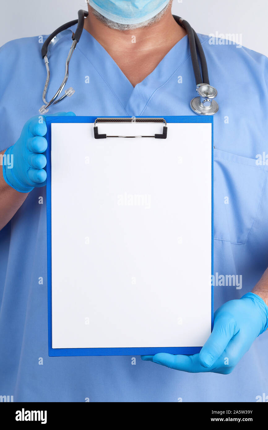 doctor in blue uniform and latex gloves holds a green holder for sheets ...