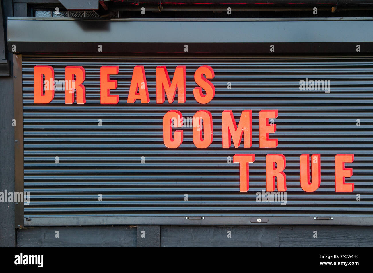 Dreams Come True motivational statement written in bright red / ornage capital letters on a black background. Stock Photo
