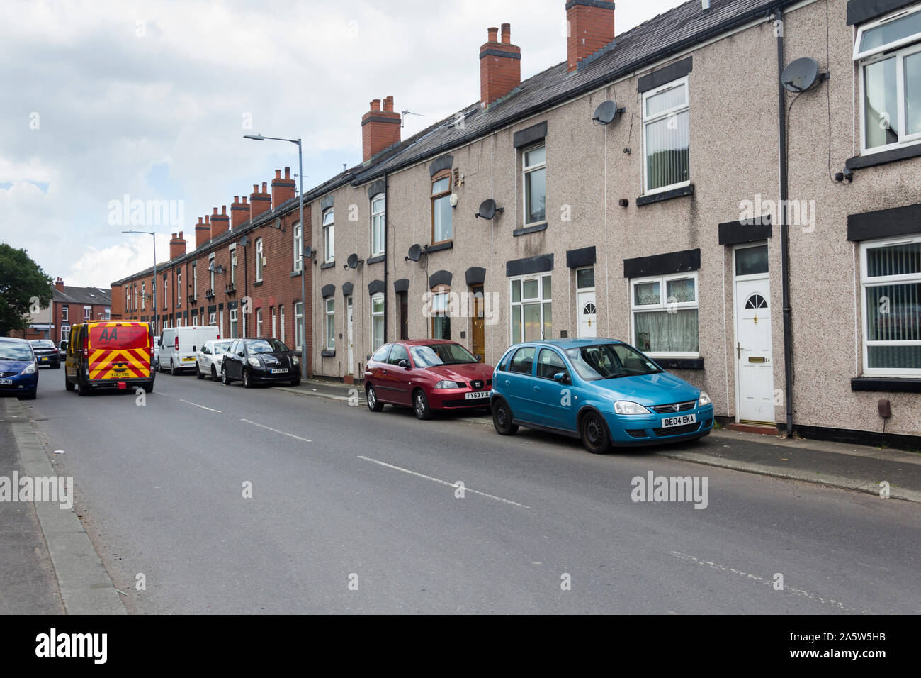 Cars parked on pavement on Campbell Street, Farnworth, in front of terraced houses with no garden and no driveway space of parking off-road. Stock Photo